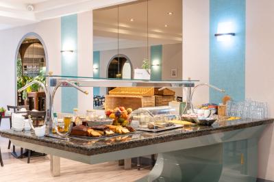 Buffet de petit-déjeuner avec viennoiseries, fruits, céréales et boissons, présenté dans une salle lumineuse.