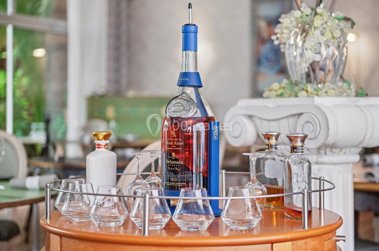 Bouteille de whisky entourée de verres et carafes sur un plateau rond dans un intérieur élégant.