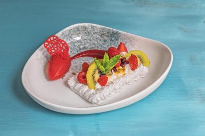 Buffet de petit-déjeuner avec viennoiseries, fruits, céréales et boissons, présenté dans une salle lumineuse.