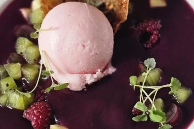 Assiette de noix de Saint-Jacques poêlées, accompagnées de légumes, agrumes et herbes fraîches sur un fond flou.