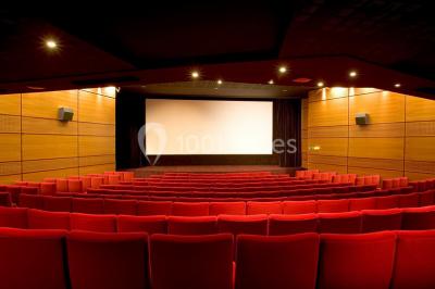 Façade d'un cinéma jaune avec plusieurs affiches de films, situé dans une rue ensoleillée.