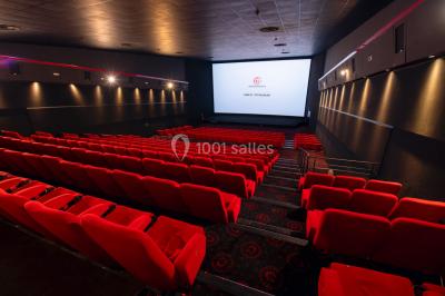 Vue extérieure d'un complexe IMAX moderne avec une esplanade dégagée et un ciel partiellement nuageux.