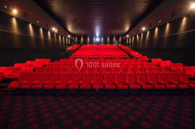 Vue extérieure d'un complexe IMAX moderne avec une esplanade dégagée et un ciel partiellement nuageux.