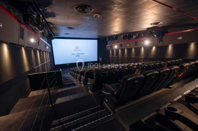 Vue extérieure d'un complexe IMAX moderne avec une esplanade dégagée et un ciel partiellement nuageux.