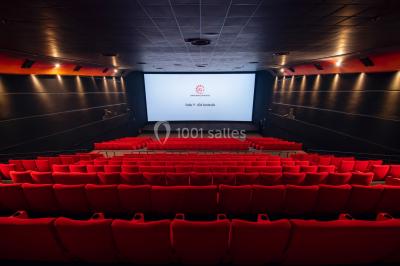 Vue extérieure d'un complexe IMAX moderne avec une esplanade dégagée et un ciel partiellement nuageux.