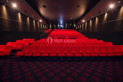 Vue extérieure d'un complexe IMAX moderne avec une esplanade dégagée et un ciel partiellement nuageux.