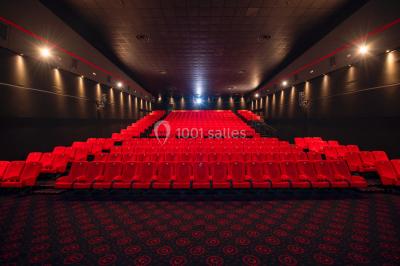 Vue extérieure d'un complexe IMAX moderne avec une esplanade dégagée et un ciel partiellement nuageux.