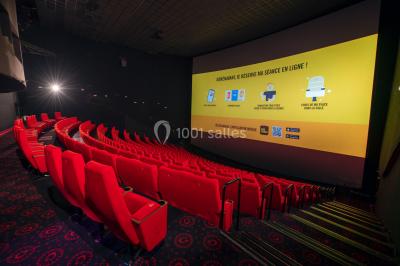 Vue extérieure d'un complexe IMAX moderne avec une esplanade dégagée et un ciel partiellement nuageux.