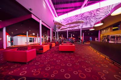 Vue extérieure d'un complexe IMAX moderne avec une esplanade dégagée et un ciel partiellement nuageux.