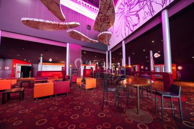 Vue extérieure d'un complexe IMAX moderne avec une esplanade dégagée et un ciel partiellement nuageux.