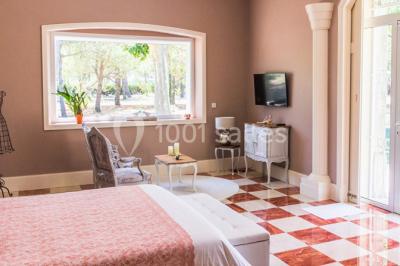 Structure en fer forgé dans un jardin, avec des invités rassemblés en arrière-plan près d'un arbre.