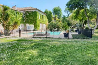 Structure en fer forgé dans un jardin, avec des invités rassemblés en arrière-plan près d'un arbre.