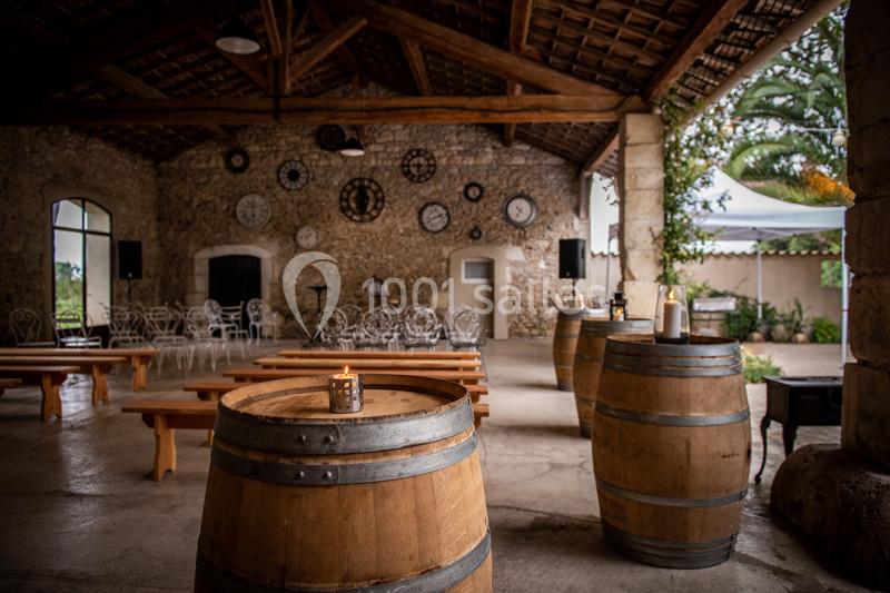 Salle en pierre avec des tonneaux en bois servant de tables, bancs en bois et décorations murales avec des horloges.