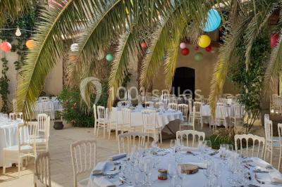 Structure en fer forgé dans un jardin, avec des invités rassemblés en arrière-plan près d'un arbre.