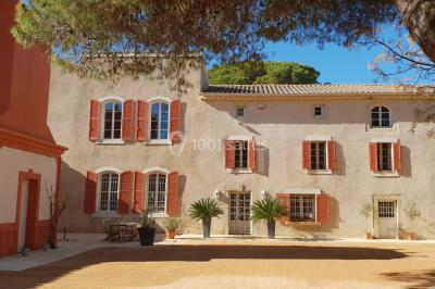 Structure en fer forgé dans un jardin, avec des invités rassemblés en arrière-plan près d'un arbre.
