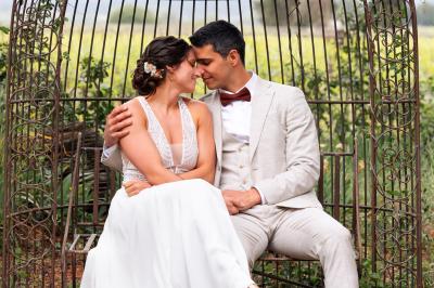 Structure en fer forgé dans un jardin, avec des invités rassemblés en arrière-plan près d'un arbre.