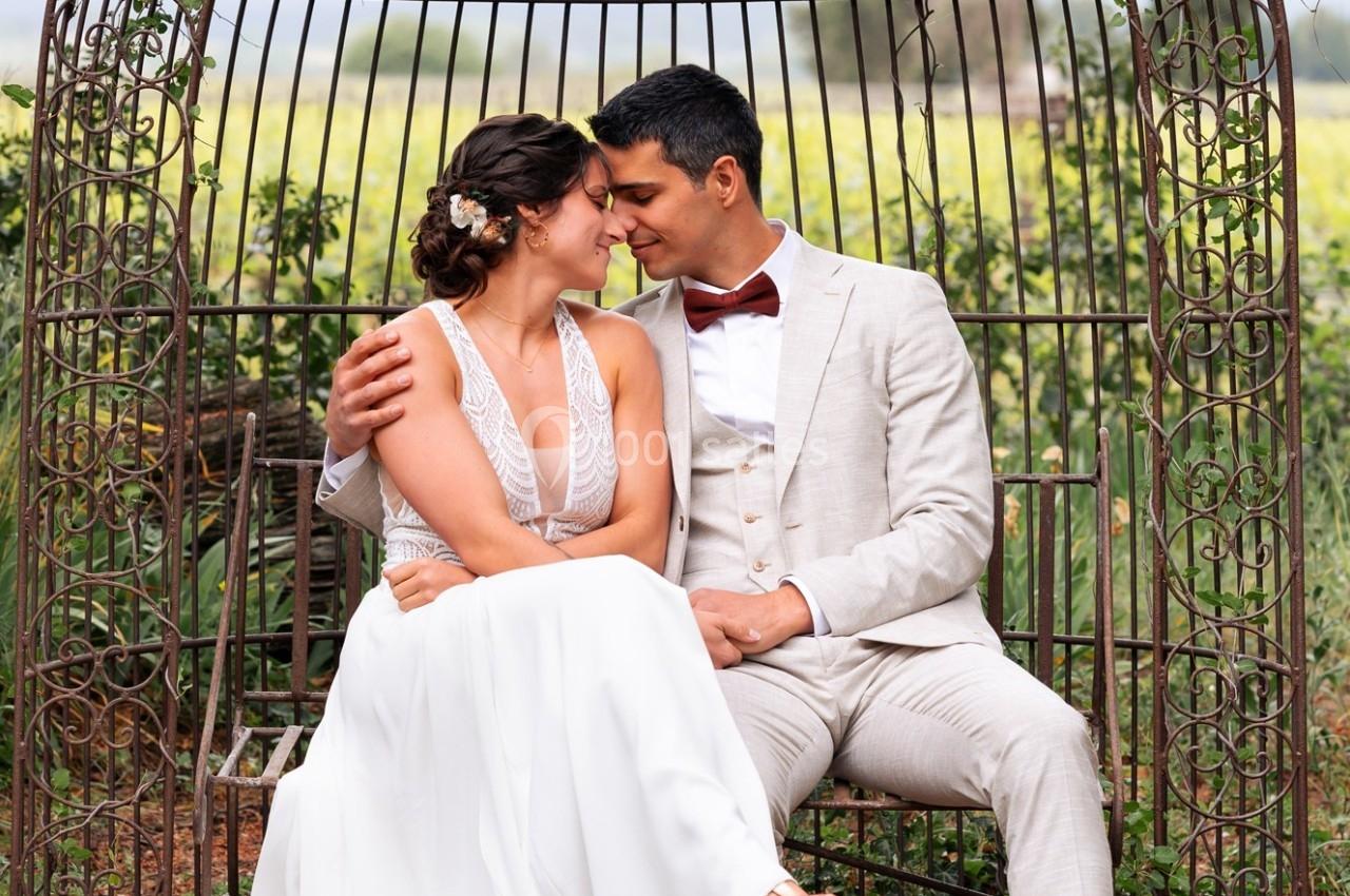 Un couple assis sur une structure métallique dans un jardin, se regardant avec tendresse.