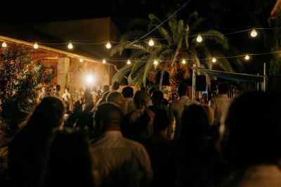 Structure en fer forgé dans un jardin, avec des invités rassemblés en arrière-plan près d'un arbre.