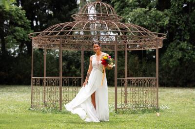 Structure en fer forgé dans un jardin, avec des invités rassemblés en arrière-plan près d'un arbre.