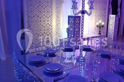 Table garnie de pâtisseries et de desserts variés, éclairée par une lumière rose et violette dans un décor festif.