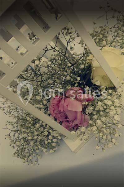 Fleurs roses et blanches entourées de gypsophile, disposées sous une structure décorative blanche.