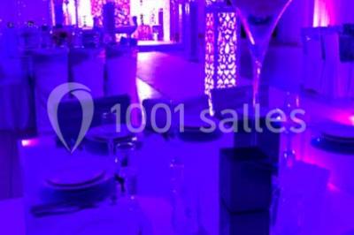 Table garnie de pâtisseries et de desserts variés, éclairée par une lumière rose et violette dans un décor festif.