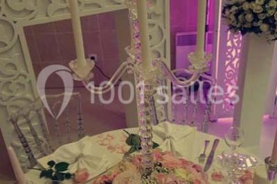 Table garnie de pâtisseries et de desserts variés, éclairée par une lumière rose et violette dans un décor festif.