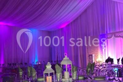 Table garnie de pâtisseries et de desserts variés, éclairée par une lumière rose et violette dans un décor festif.