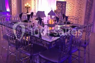 Table garnie de pâtisseries et de desserts variés, éclairée par une lumière rose et violette dans un décor festif.