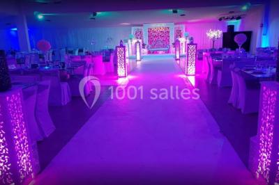 Table garnie de pâtisseries et de desserts variés, éclairée par une lumière rose et violette dans un décor festif.