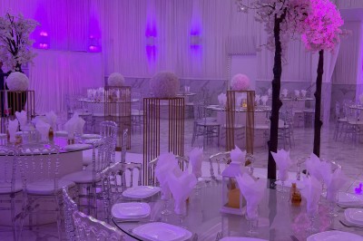 Table dressée avec des amuse-bouches variés, bougies blanches et décorations florales, en extérieur.