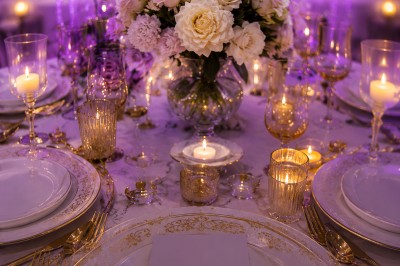 Table de réception élégamment décorée avec des fleurs blanches et rouges, bougies allumées et vaisselle raffinée.