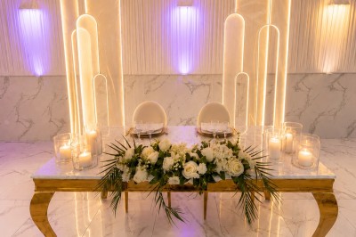 Table de réception élégamment décorée avec des fleurs blanches et rouges, bougies allumées et vaisselle raffinée.