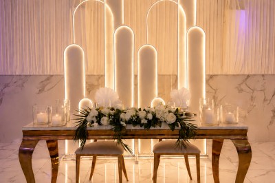 Table de réception élégamment décorée avec des fleurs blanches et rouges, bougies allumées et vaisselle raffinée.