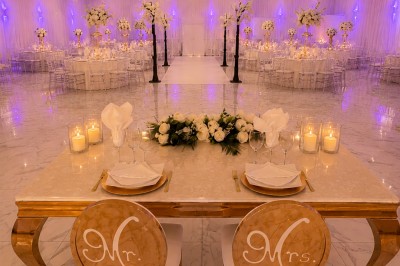 Table de réception élégamment décorée avec des fleurs blanches et rouges, bougies allumées et vaisselle raffinée.