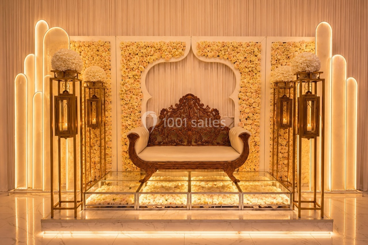 Décor élégant avec un canapé sculpté, fond de fleurs pastel et lanternes dorées sur un sol en marbre.