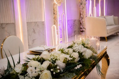 Table de réception élégamment décorée avec des fleurs blanches et rouges, bougies allumées et vaisselle raffinée.