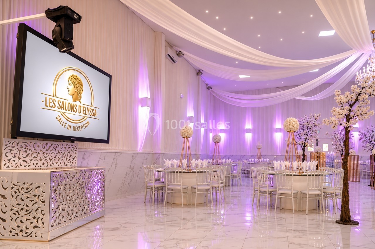 Salle de réception élégante avec tables décorées, éclairage violet et écran affichant un logo.