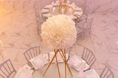 Table de réception élégamment décorée avec des fleurs blanches et rouges, bougies allumées et vaisselle raffinée.