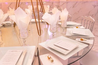 Table de réception élégamment décorée avec des fleurs blanches et rouges, bougies allumées et vaisselle raffinée.