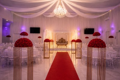 Table de réception élégamment décorée avec des fleurs blanches et rouges, bougies allumées et vaisselle raffinée.