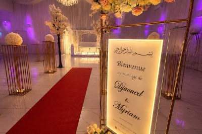 Table de réception élégamment décorée avec des fleurs blanches et rouges, bougies allumées et vaisselle raffinée.