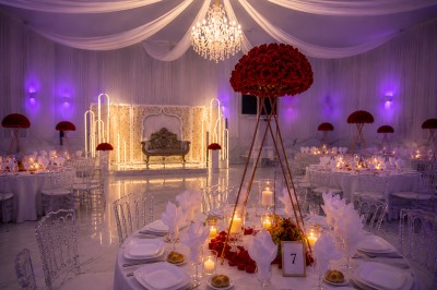 Table de réception élégamment décorée avec des fleurs blanches et rouges, bougies allumées et vaisselle raffinée.