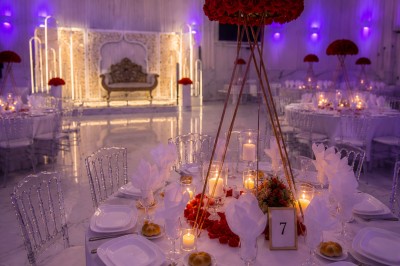 Table de réception élégamment décorée avec des fleurs blanches et rouges, bougies allumées et vaisselle raffinée.