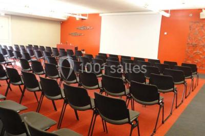 Salle circulaire avec tables rondes dressées, nappes grises et serviettes vertes, entourée de baies vitrées donnant sur des…