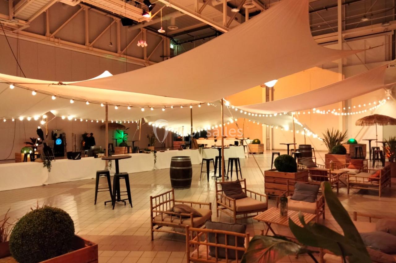 Espace intérieur décoré avec des voilages suspendus, guirlandes lumineuses, mobilier en bois et ambiance chaleureuse.