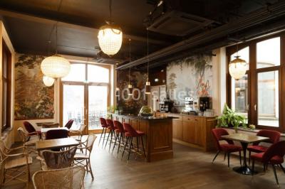 Personnes rassemblées sous une tente verte sur une terrasse, avec des plantes en pot et des clochers en arrière-plan.
