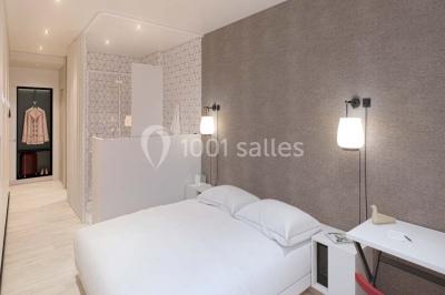 Salle de bain moderne avec murs sombres, douche à l'italienne et vue sur un sauna en bois éclairé.