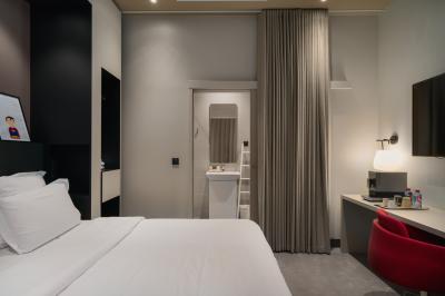 Salle de bain moderne avec murs sombres, douche à l'italienne et vue sur un sauna en bois éclairé.