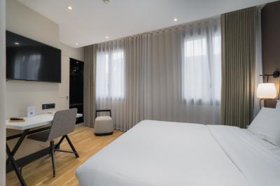 Salle de bain moderne avec murs sombres, douche à l'italienne et vue sur un sauna en bois éclairé.